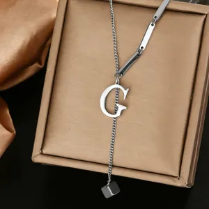 Detailed close-up of a stainless steel initial G letter Y necklace on a luxury gold jewelry box.