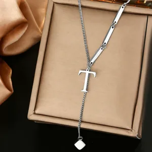 Close-up detail of stainless steel letter T pendant necklace, delicate chain and metallic finish.