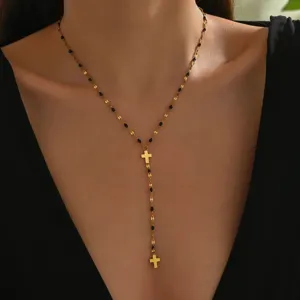 Collana con croce in acciaio al titanio placcato oro e perle nere, catena elegante.