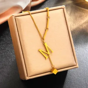 Vue rapprochée du collier pendentif lettre M doré, bijou minimaliste en acier au titane.
