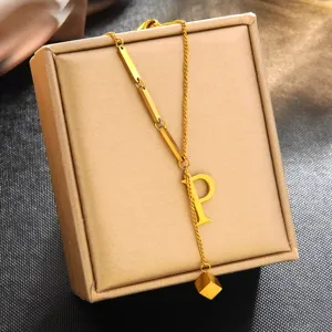 Vue rapprochée du collier pendentif lettre P en acier titane plaqué or 18k avec breloques.