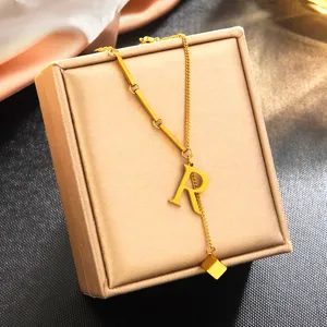 Vue détaillée du collier pendentif lettre R en acier inoxydable plaqué or, élégante boîte bijoux.