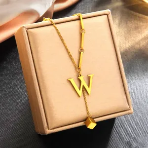 Gros plan détaillé d'un collier pendentif lettre W minimaliste en acier inoxydable dor.