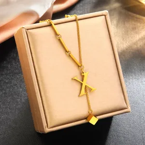 Élégant collier pendentif lettre X en acier inoxydable doré, détail de bijoux minimalistes chic.