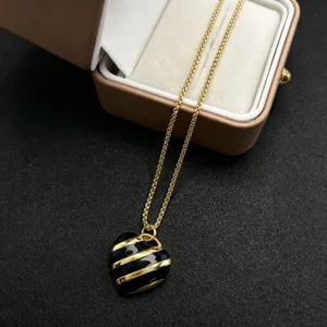 Nahaufnahme einer vergoldeten Kette mit schwarz-goldem Herz-Anhänger in Schmuckschatulle.