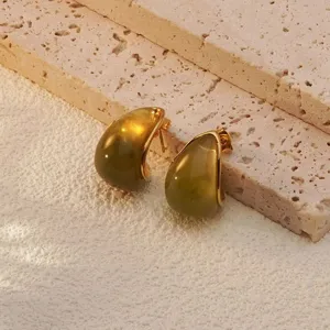 Close-up detail of stylish green teardrop earrings on textured stone background, elegant design.