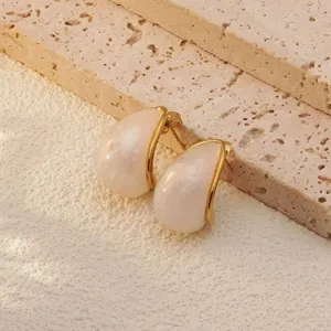 Close-up detail of stylish gold-trimmed teardrop earrings with a glossy white resin insert.