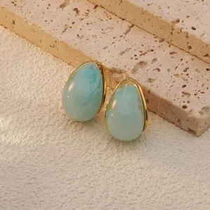 Stainless steel teardrop earrings with blue marble texture and gold rim for women detail shot.