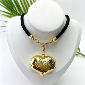 Close-up of the gold-plated double-sided 3D heart pendant and black cord necklace detail.