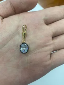 Dettaglio ravvicinato del ciondolo bicolore placcato in rame con gemma ovale trasparente.