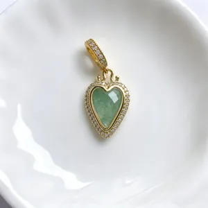 Detailaufnahme eines vintage herzförmigen grünen stein anhängers mit funkelnden zirkonias.