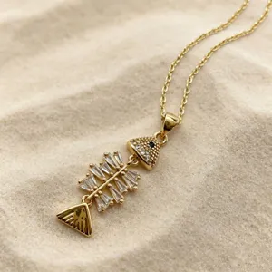 Close-up detail of a delicate gold-plated fish skeleton pendant necklace with sparkling zirconia stones.