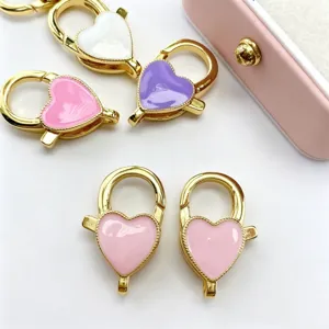 Gros plan de fermoirs mousquetons en cœur colorés, anneaux à ressort émaillés bijoux DIY.