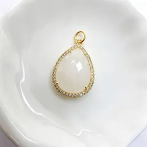 Detailaufnahme eines tropfenförmigen weißen Stein-Anhängers mit Zirkonia in Gold.
