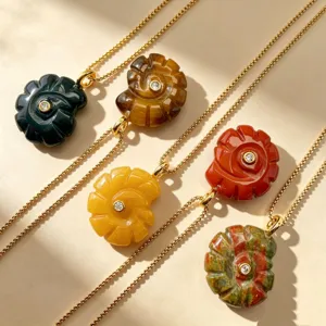 Collier pendentif conque ammonite sculptée en pierre naturelle avec chaîne dorée et cristal.