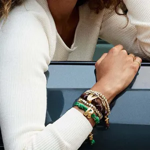Vista detallada de pulseras apiladas de cuerda colorida y letras de alfabeto de metal mujer.