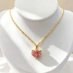 Gros plan détaillé du collier pendentif en zircon cœur rose scintillant sur présentoir blanc.