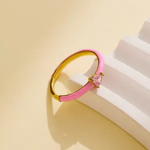 Close-up detail shot of a dainty stainless steel ring featuring pink enamel and a heart crystal.