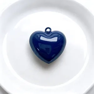 Blue glossy heart pendant detail shot, stylish copper baked paint DIY jewelry accessory.