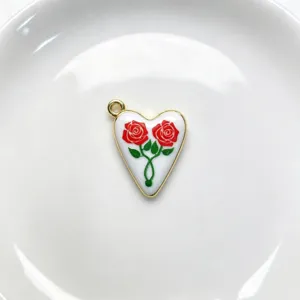 Detail shot of a charming heart enamel pendant featuring dual red roses and gold trim.