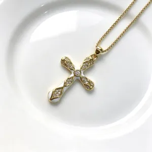 Pendentif collier croix en or avec serti micro-pavé en zircone cubique et détails blancs élégants.