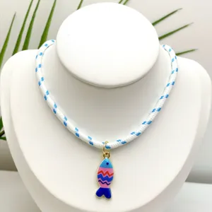 Gros plan détaillé d'un collier pendentif poisson émaillé coloré avec un cordon rayé.