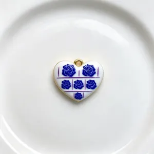 Close-up detail of the heart pendant showcasing blue rose patterns and glossy gold edges.