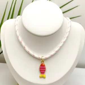Gros plan du pendentif poisson coloré émaillé à rayures sur un collier en corde tressée.