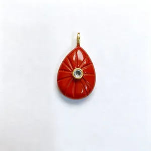 Detailed view of carved red teardrop gemstone pendant with sparkling center crystal accent.