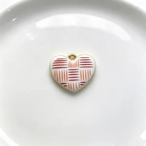 Detailed shot of the elegant enamel heart pendant with red geometric pattern and gold rim.
