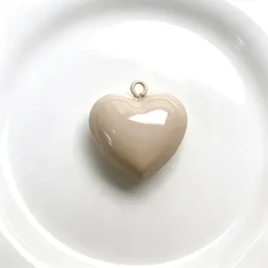 Close-up detail of glossy beige heart pendant charm for DIY handmade jewelry necklace making.