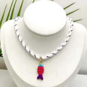 Gros plan détaillé du collier pendentif poisson émaillé coloré sur un support blanc.