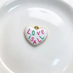 Close-up detail of the white enamel heart pendant with colorful love text and gold trim.