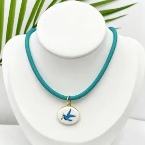 Primer plano detallado del collar con colgante de esmalte de golondrina azul vintage con borde.