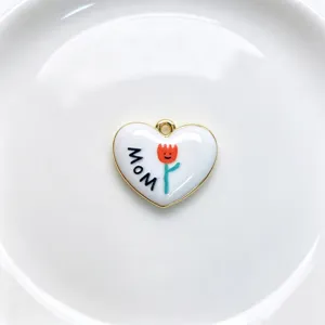 Close-up detail of a white enamel heart pendant featuring a cute tulip and MOM lettering.