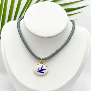 Collar con colgante ovalado de golondrina esmaltada vintage con cadena de cuerda gris.