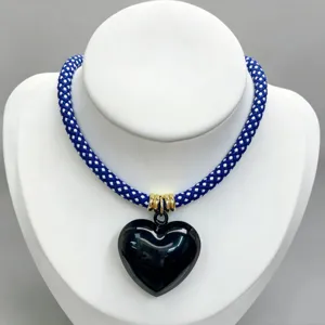 Detailed view of blue white braided rope necklace with glossy black heart pendant and gold rings.