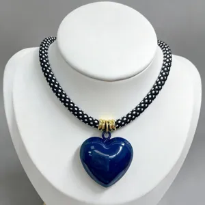 Black and white woven rope necklace with glossy dark blue heart pendant, fashion jewelry detail.