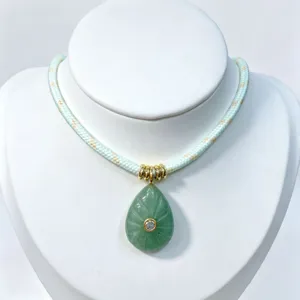 Detailed view of teardrop green stone pendant necklace with gold accent and zircon inlay.
