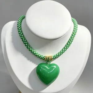 Green white braided rope necklace with glossy green heart pendant jewelry detail view.