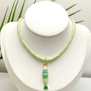Détail en gros plan d'un collier en corde tressée vert clair avec un pendentif poisson.