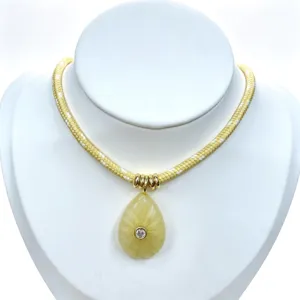 Detailed shot of a yellow braided rope necklace featuring a teardrop crystal pendant.
