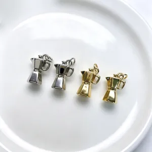 Gros plan détail de charms mini cafetière en métal, pendentifs de bijoux DIY, or et argent.