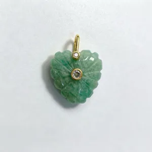 Close-up detail of green carved heart crystal pendant with gold bail and inset zircon stones.