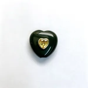 Detailaufnahme des dunklen Herz-Stein-Anhängers mit gelbem Kristall im Goldrahmen Schmuck.