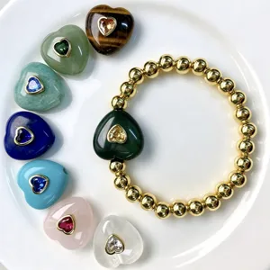 Detailansicht goldener Perlenarmbänder mit Zirkon-Herzanhänger und bunten Edelsteinherzen.