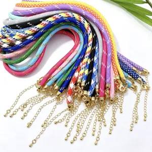 Close-up detail of colorful woven braided cord necklaces with gold chains and lobster clasps.