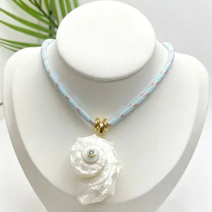 Collana con ciondolo in conchiglia naturale con corda intrecciata blu e dettagli dorati.