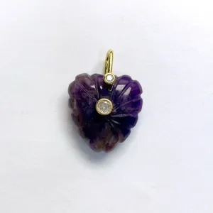 Close-up of a carved purple crystal heart pendant with gold bail and inlaid zircon stones.