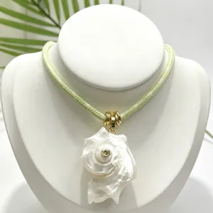 Dettaglio collana con ciondolo conchiglia naturale, cordino verde con finiture dorate.